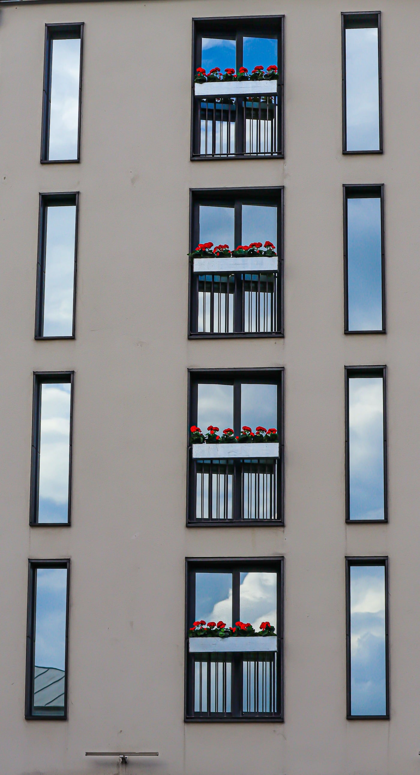 Fassade mit schmalen, vom Fensterbauer eingebauten Fensterelementen und Blumenkästen
