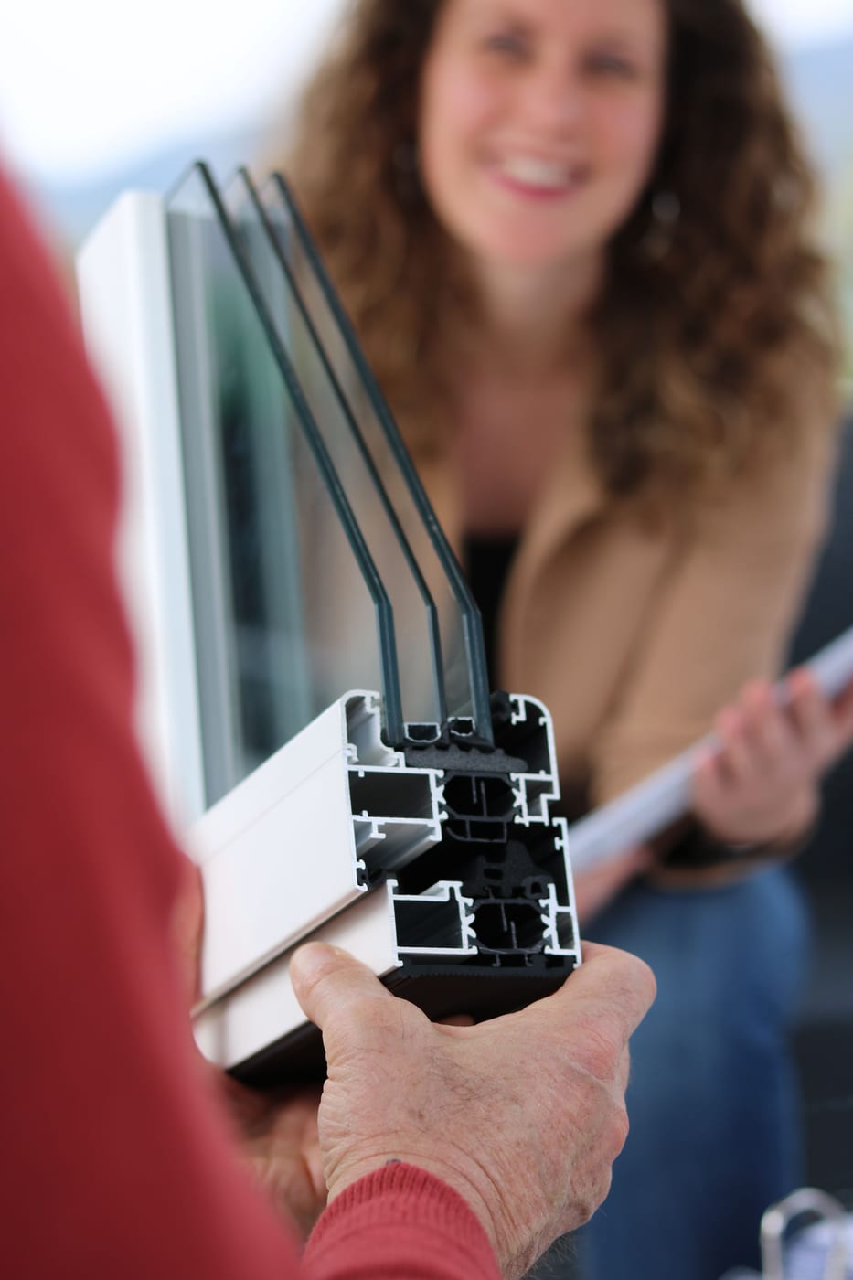 Fensterbauer erklärt im Beratungsgespräch das Schnittmodell eines dreifach verglasten Fensterprofils